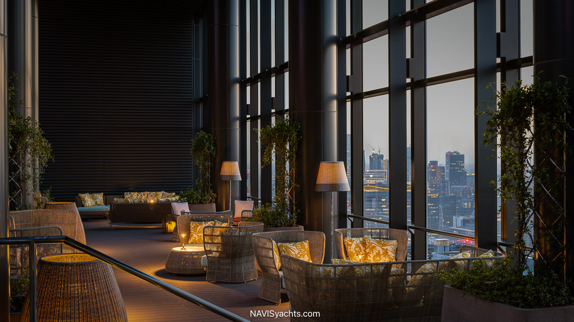 Panoramic view from a room at the Bvlgari Hotel Tokyo, looking out over the expansive city skyline with floor-to-ceiling windows framing the serene Imperial Palace Gardens below.