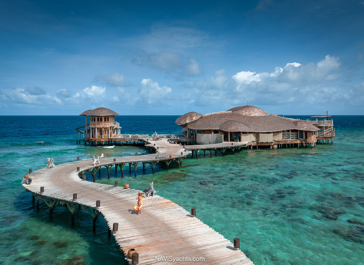 The overwater dining complex "Out of the Blue" at Soneva Fushi, showcasing its two-story structure with open-air design, thatched roof, and integration with the turquoise waters of the Baa Atoll.