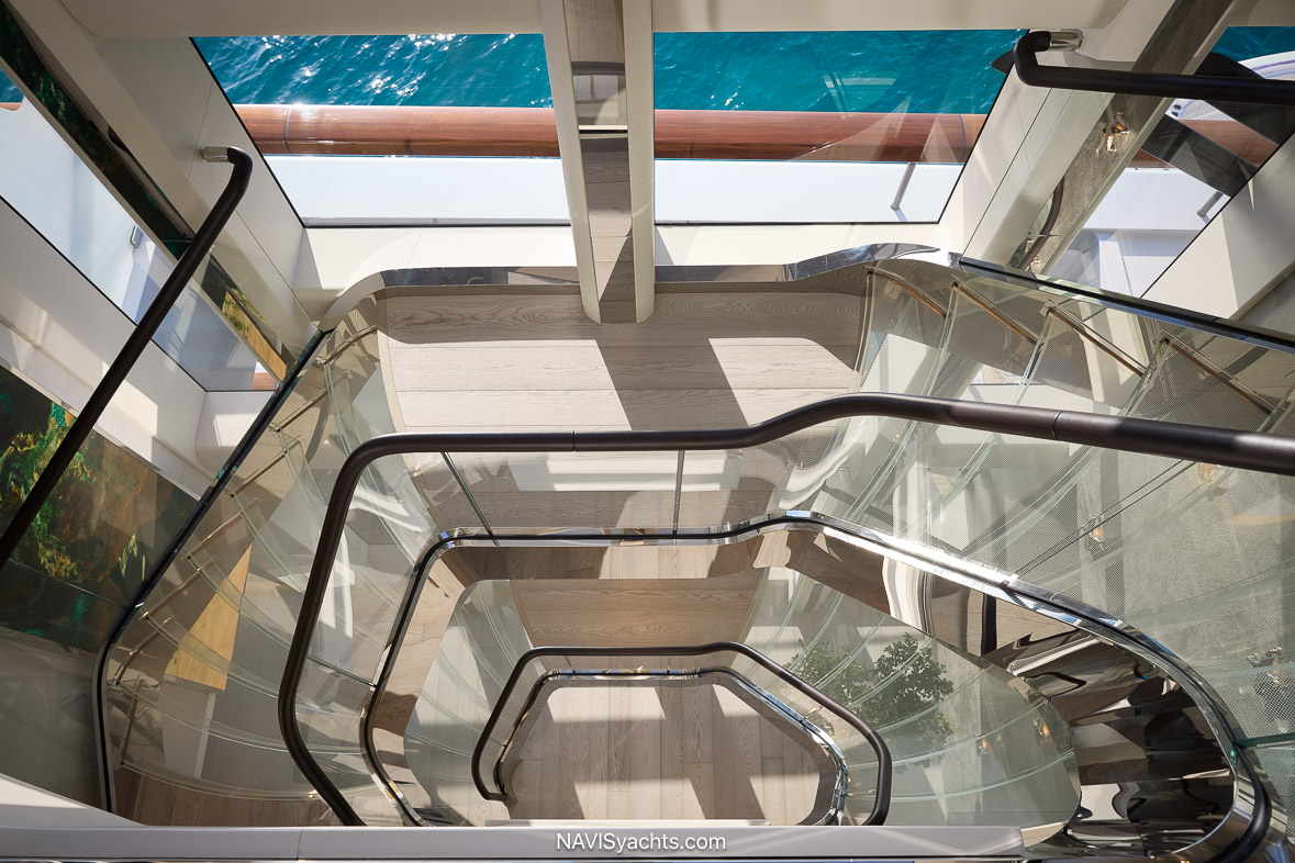 Three-deck glass atrium aboard Feadship Vanish with floating staircase and guest elevator