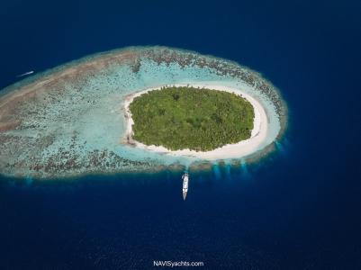 Luxury yacht M/Y Galileo anchored near an untouched island in the Maldives, surrounded by turquoise water and coral reef