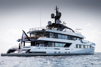 The 60-meter Amels motor yacht Entourage gliding across the water, showcasing the Espen Øino-designed exterior with its strong bow and elongated, continuous windows along the main deck.
